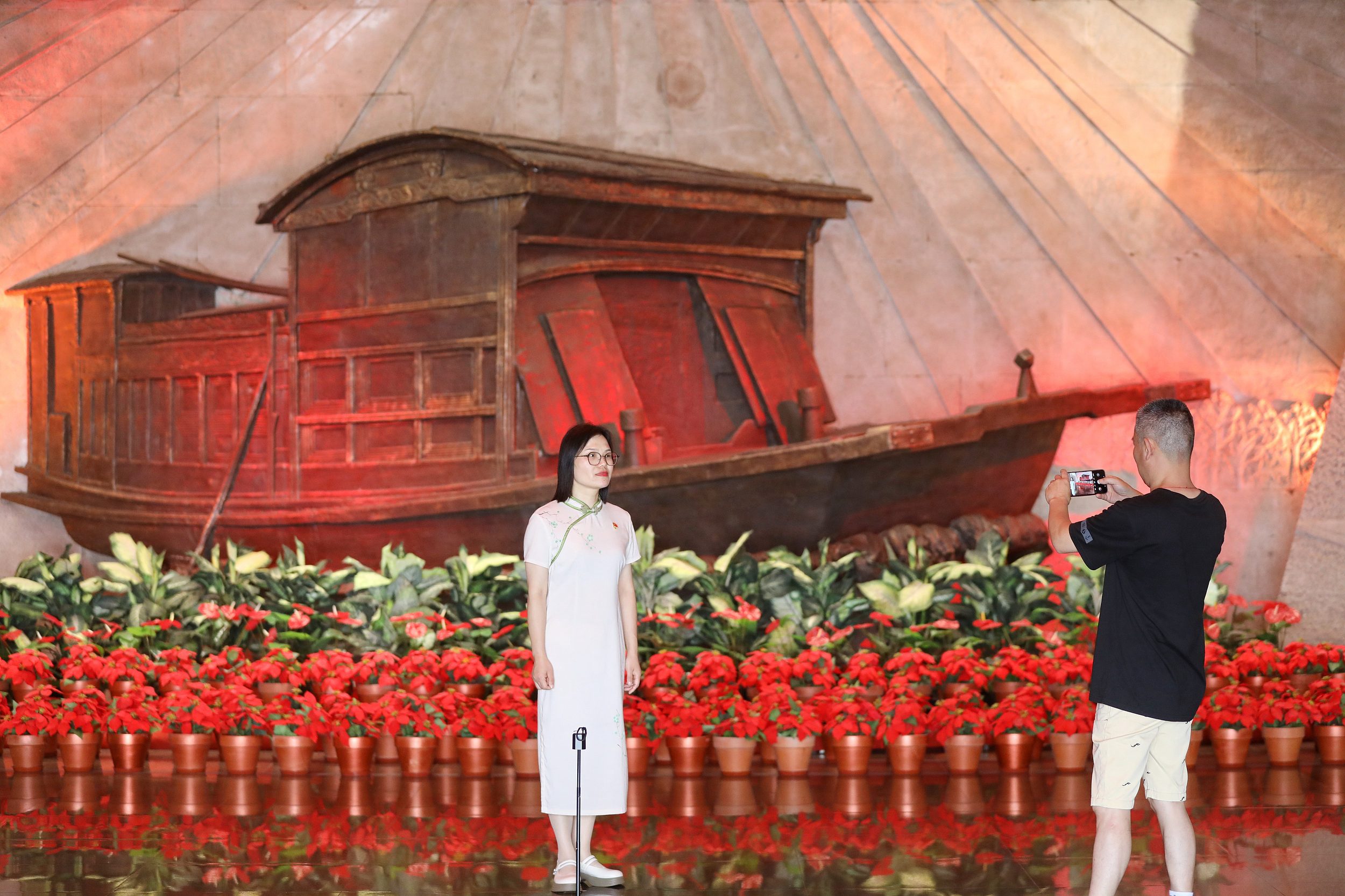 2025年6月24日，浙江嘉興，游客在南湖革命紀(jì)念館與紅船雕塑合影。（圖片來源：視覺中國）